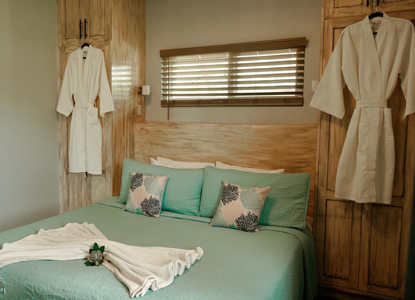 Villa bedroom with king sized bed, two spa robes hang on the closet doors