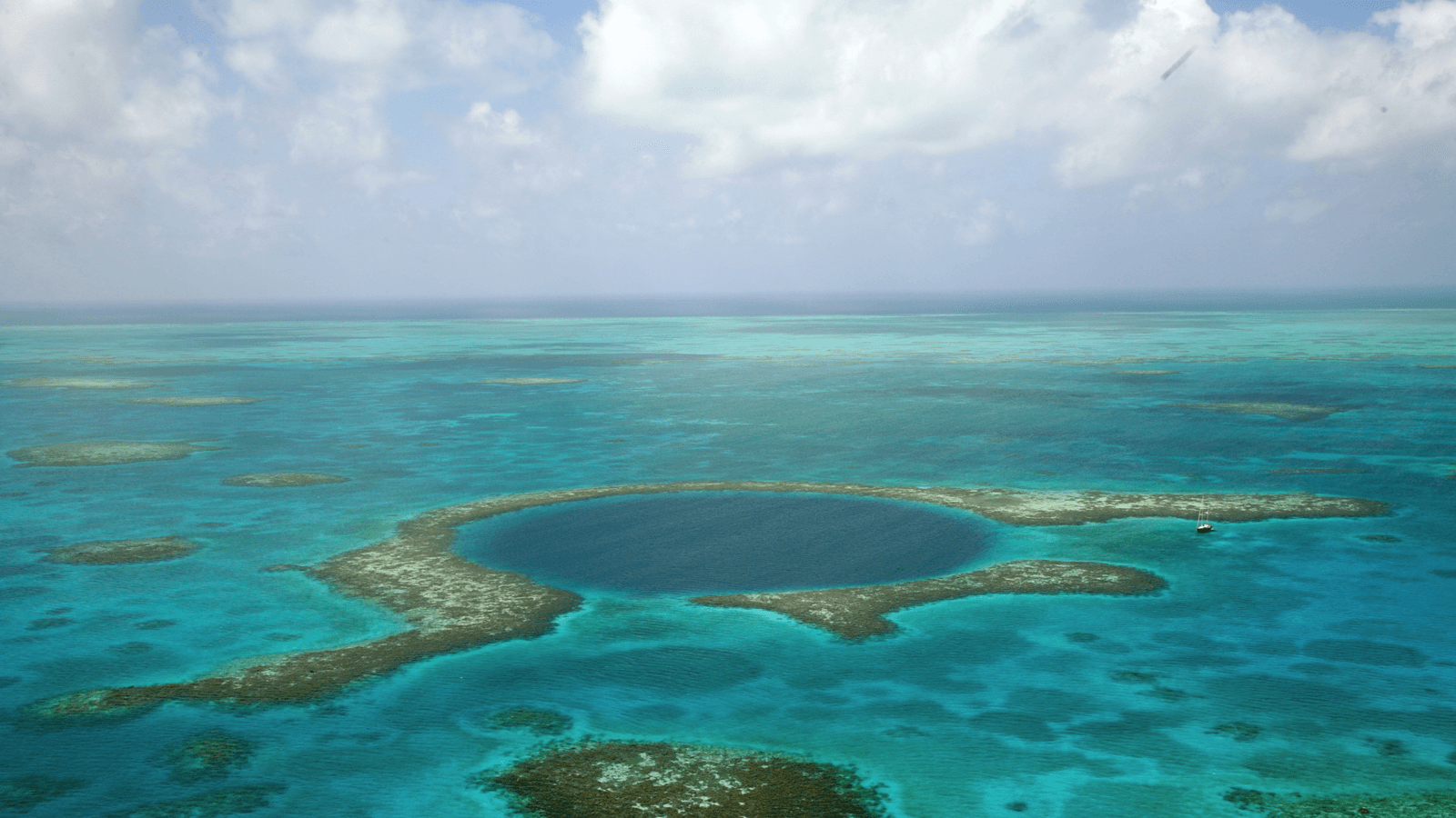 An aerial view of the Great Blue Hole surrounded by turquoise waters and coral reefs.