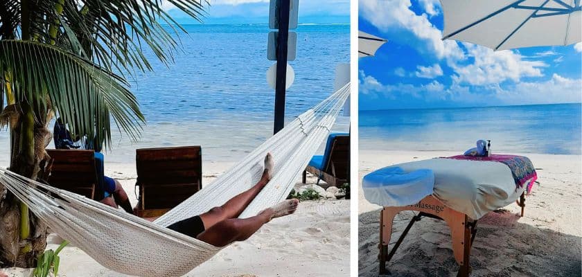 A person relaxes in a hammock by the beach, beside a massage table set up on the sand under an umbrella.