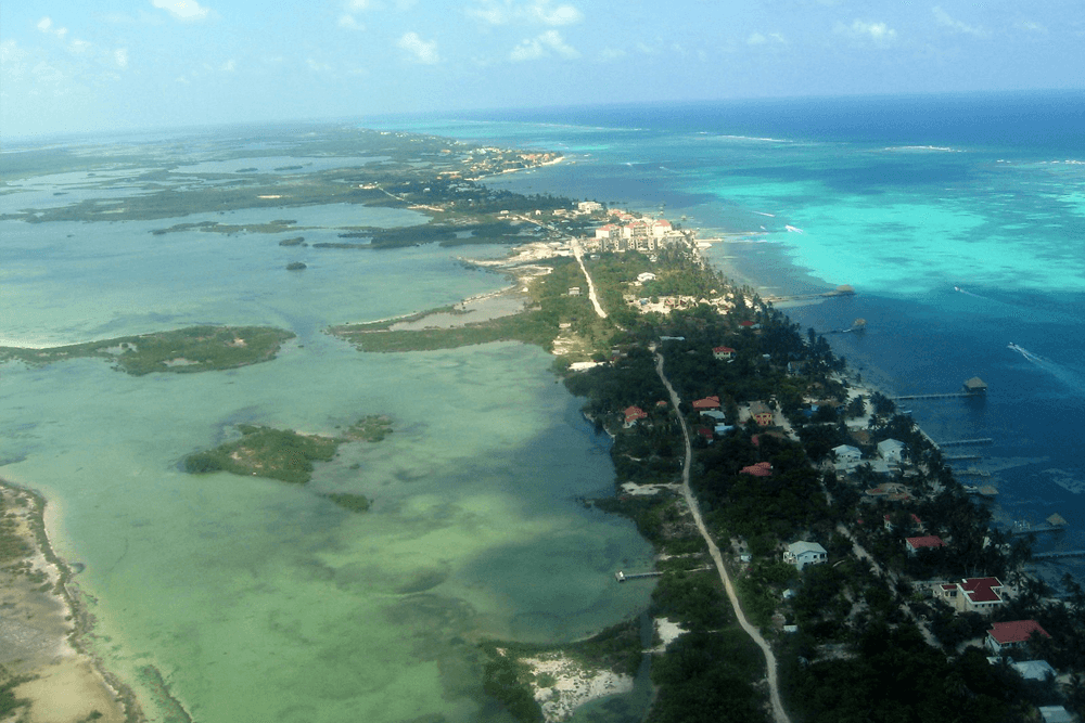 Aerial view of a coastal region featuring turquoise waters, mangroves, and a winding road along the shoreline.