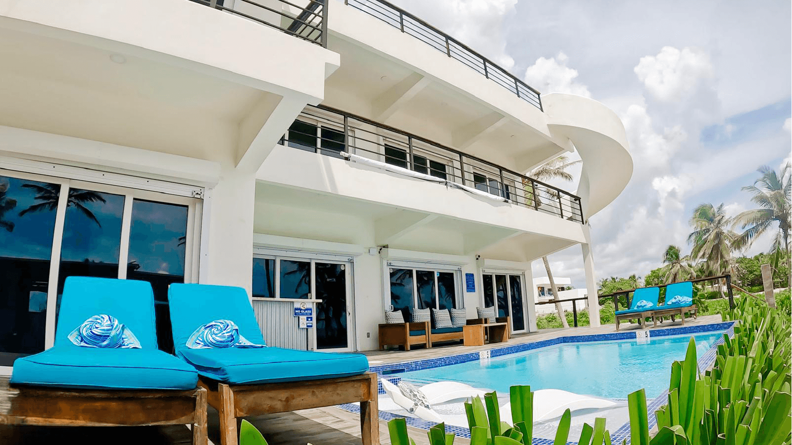 Modern villa with a pool surrounded by tropical greenery and lounge chairs.