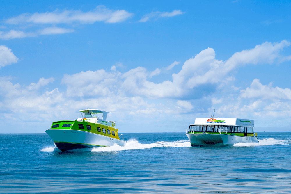 Two boats navigate through calm blue waters under a partly cloudy sky.