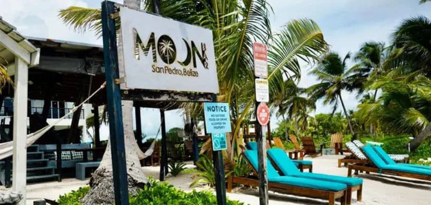 Moon Bar sign at Mangata Villas in San Pedro, Belize, with turquoise lounge chairs, palm trees, and beach hammocks nearby.
